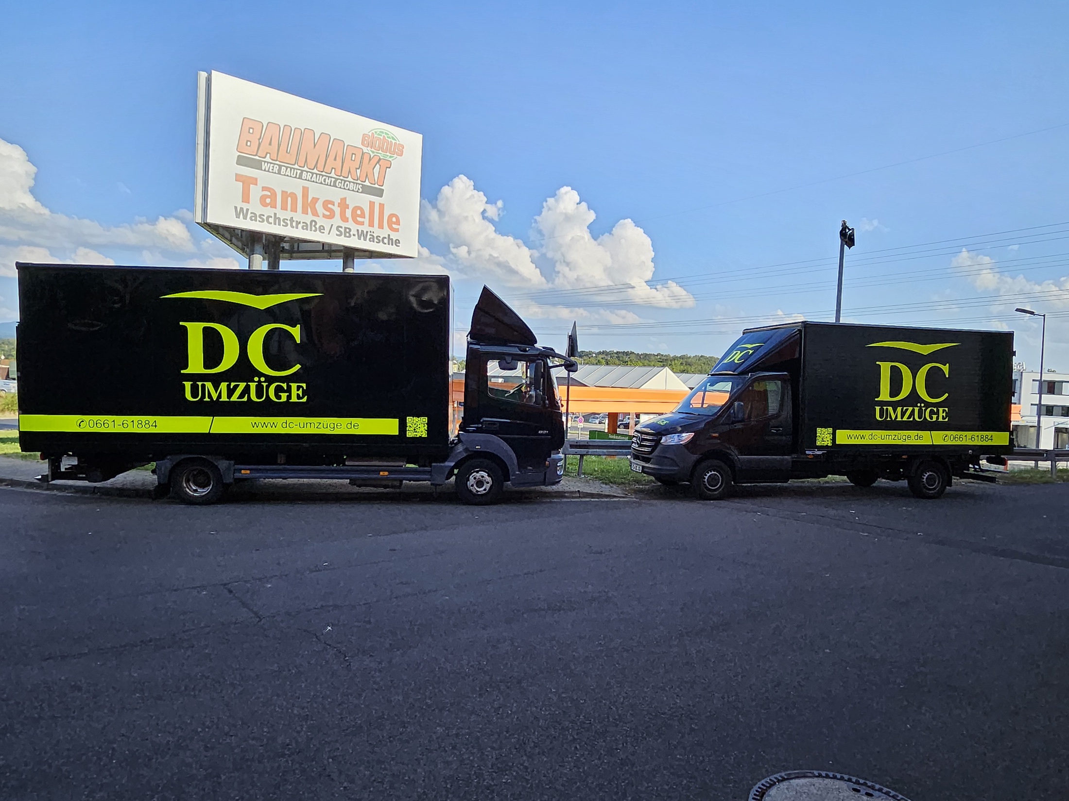 Two black DC-Umzüge moving vehicles with neon-yellow branding.