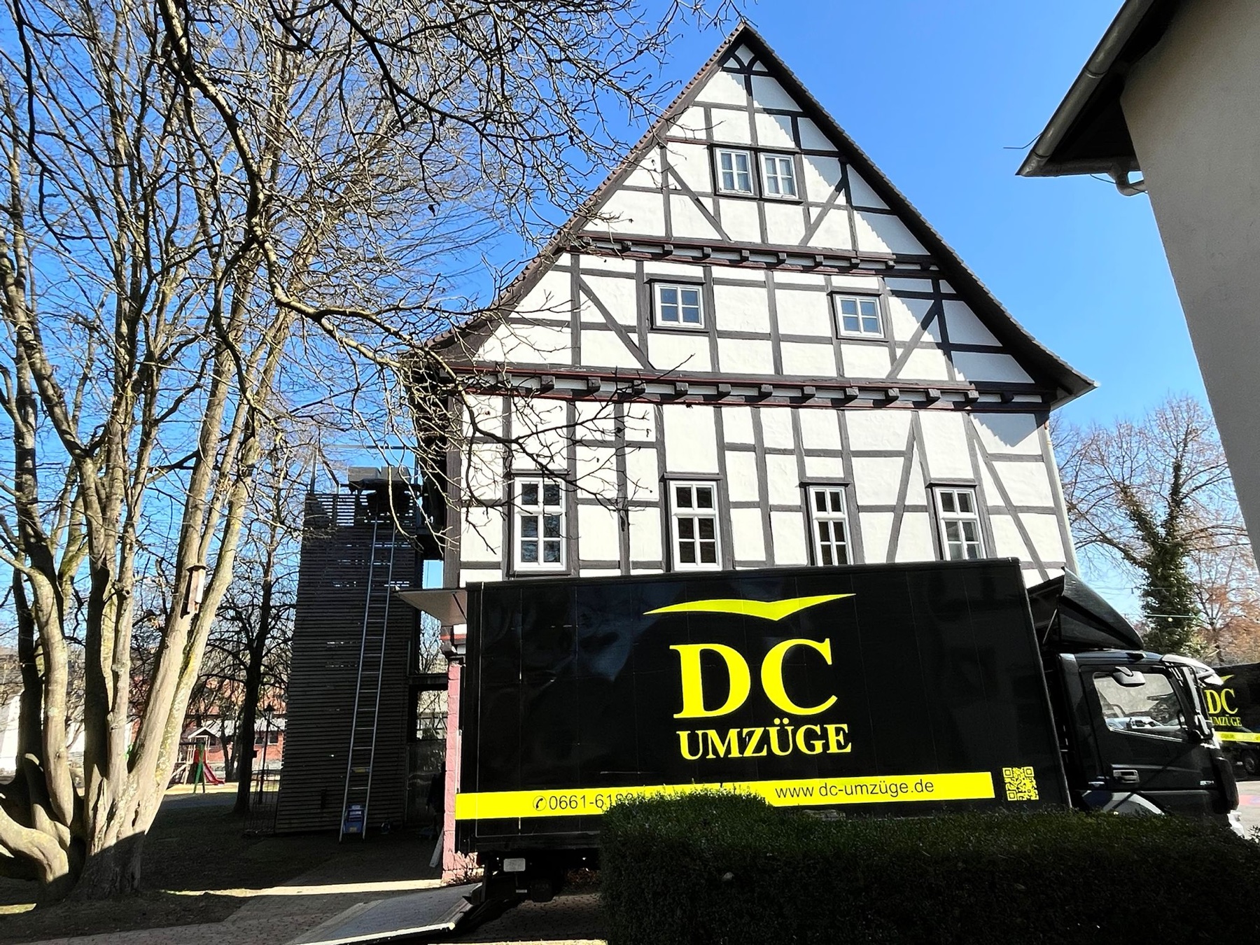 Ein schwarz folierter Lkw von DC-Umzüge steht vor einem Fachwerkgebäude in der Region.