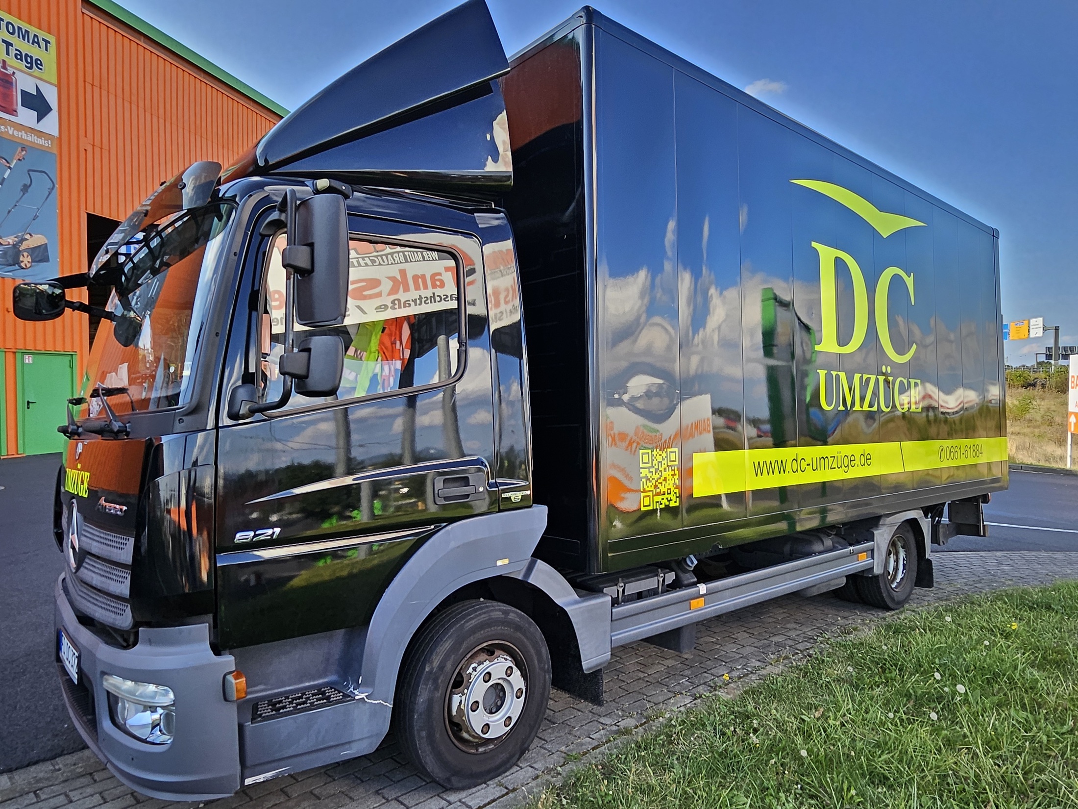 A black DC-Umzüge truck with neon-yellow branding.